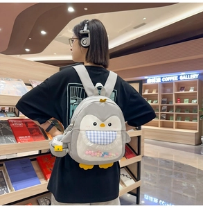Detail of cute penguin backpack with colorful pompoms and blue checkered bib detail