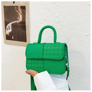 Détail du mini sac à main vert avec coutures croisées et textures de cuir tressé