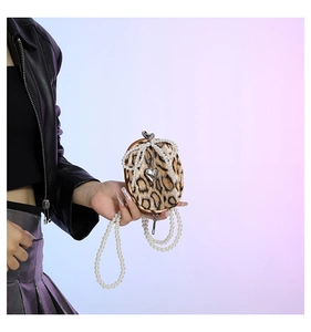 Detail of leopard print mini bag with pearl bow and silver heart pendant on chain