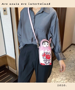 Detail of pink Russian doll crossbody bag with floral patterns and gold hardware