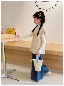 Détail de gilet en peluche beige pour fille, chemise à pois et pantalon en jean bleu