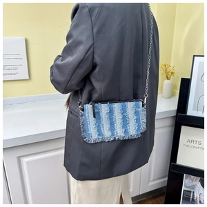 Close-up of denim crossbody bag with blue and white stripes and frayed edges detailing