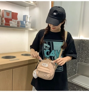 Détail du sac bandoulière agneau beige avec pendentif peluche et poches zippées