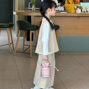 Pink drawstring bucket bag for girls with mini chain handle in a stylish boutique setting