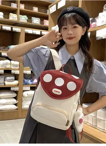 Detail of red mushroom backpack with white dots and a plush bunny charm on the side