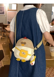 Détail du sac à bandoulière poussin avec poche jaune smile et breloque peluche blanche