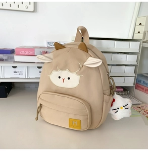 Detailansicht der Lamm-Stickerei und des Plüschstern-Anhängers am beigen Rucksack