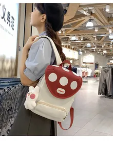 Detail of red and white polka dot flap backpack with a cute white rabbit plush keychain