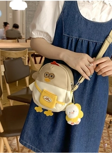 Détail d'un sac bandoulière poussin avec pendentif tournesol et texture en toile