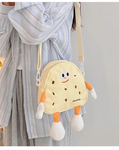 Close-up of yellow cartoon biscuit shoulder bag with white adjustable strap on a model