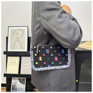 Detail of denim crossbody bag with colorful embroidery and trendy fringe edges