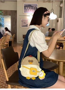 Détail d'un sac bandoulière poussin mignon avec pendentif en peluche dans un décor de café