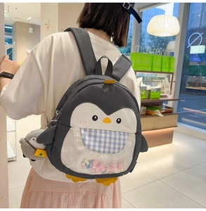 Detail of penguin backpack with colorful decorative balls inside a transparent window
