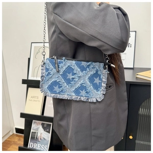 Close-up of denim crossbody bag with star patterns and frayed edges on silver chain