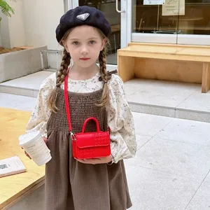 Sac à main rouge pour enfants avec rabat tressé et fermoir métallique en scène extérieure