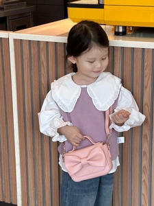 Détail d'un sac à main rose pour fille avec un grand nœud et texture en cuir