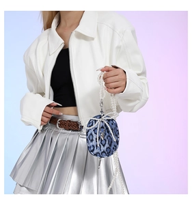 Detail of mini blue leopard print bag with pearl bow and elegant long chain strap