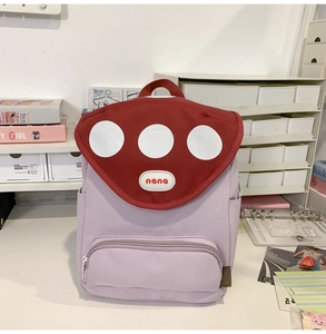Detail of cute purple mushroom backpack with red dot lid and side pockets on a desk
