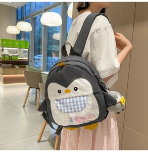 Close-up of cute penguin backpack with transparent pocket and colorful pompom detail