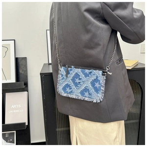 Detail of denim crossbody bag with star pattern and silver chain on female model
