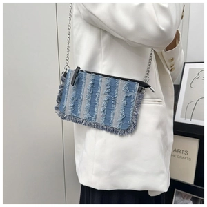 Detail of blue denim crossbody bag featuring frayed fringe texture and silver chain strap