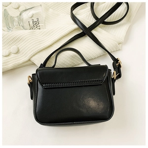 Détail d'un mini sac à main noir en simili cuir avec poignée et boucles dorées chic