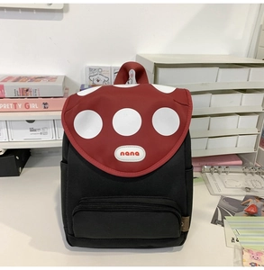 Detail of cute mushroom backpack with red polka dot flap and side pocket on desk