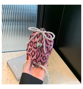 Detailed view of pink leopard print mini bag with pearl strap and beaded bow charm