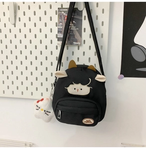 Vue détaillée du sac bandoulière en toile noire avec écusson mouton et breloque Hello Kitty