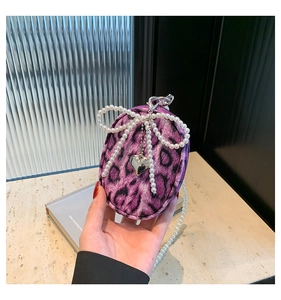 Detail of purple leopard print mini bag with pearl bow and silver heart pendant