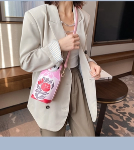 Pink Russian doll crossbody bag in PU leather featuring red floral patterns on a model