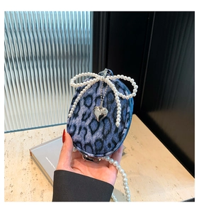 Detailed shot of leopard print mini bag with pearl bow and silver heart pendant