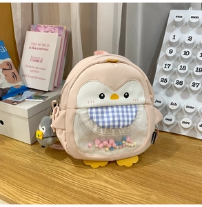Pink penguin backpack featuring transparent PVC window with colorful pom-poms and charm