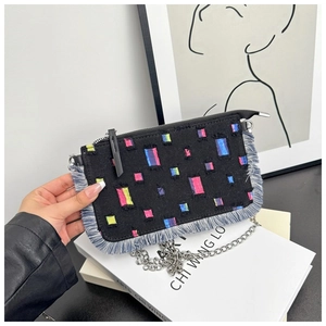 Detail of black denim crossbody bag featuring colorful embroidery and frayed fringe trim