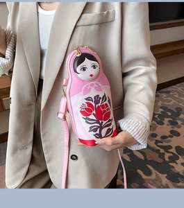 Close-up of pink Russian doll crossbody bag with floral painted design and gold zippers