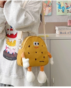 Detail of yellow cookie-shaped kids' crossbody bag featuring plush arms and legs
