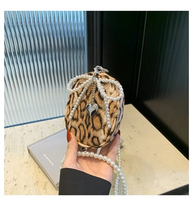 Detail of leopard print mini bag with pearl bow, heart pendant and stylish chain strap