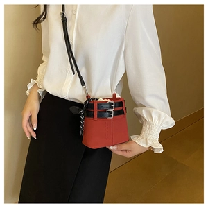 Dettaglio di una borsa a secchiello rossa con coulisse e fibbie decorative nere