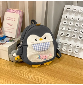 Close-up of penguin backpack with colorful balls in blue checkered transparent pocket