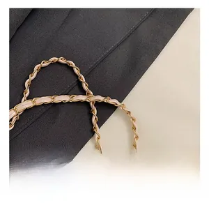 Détail de la bandoulière en chaîne dorée entrelacée de cuir beige pour sac de fille