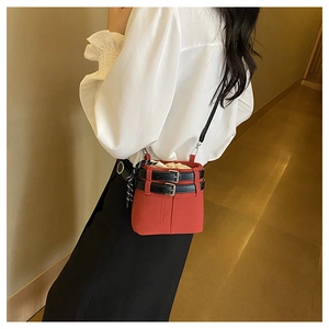 Détail d'un sac seau rouge avec boucle décorative noire et fermeture par cordon serrage