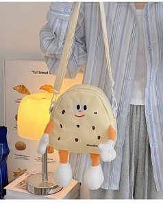 Cute cookie-shaped crossbody bag with plush limbs shown on person in a cozy setting