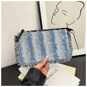 Detailed macro view of denim crossbody bag with striped fringe and silver chain strap