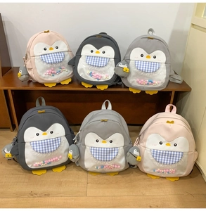 Close-up of cute penguin backpacks with colorful plush balls in transparent pockets