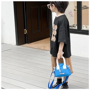 Outdoor shot of a child carrying a blue nylon mini crossbody bag with white handles