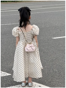 Détail d'un sac à bandoulière matelassé rose avec nœud pour fille sur une robe d'été à pois