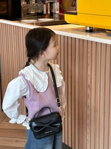 Détail du mini sac bandoulière noir avec grand nœud et bandoulière à boucle dorée
