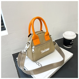 Detail of mini nylon bag with bright orange handle and adjustable strap on a book