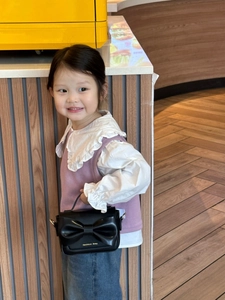 Vue détaillée du mini sac bandoulière pour enfant en cuir PU noir avec un grand nœud décoratif