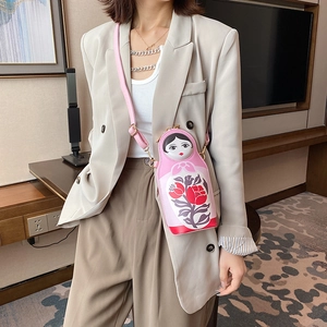 Pink Matryoshka doll shaped crossbody bag with floral patterns on a fashion model